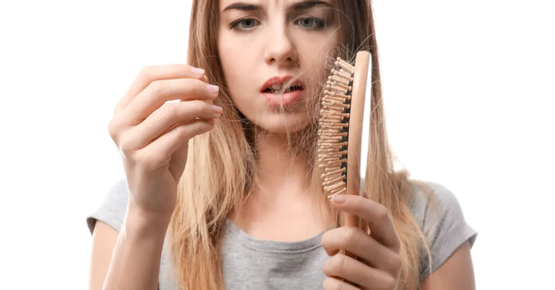 Woman looking at a hairbrush showing the need for a Hair loss treatment