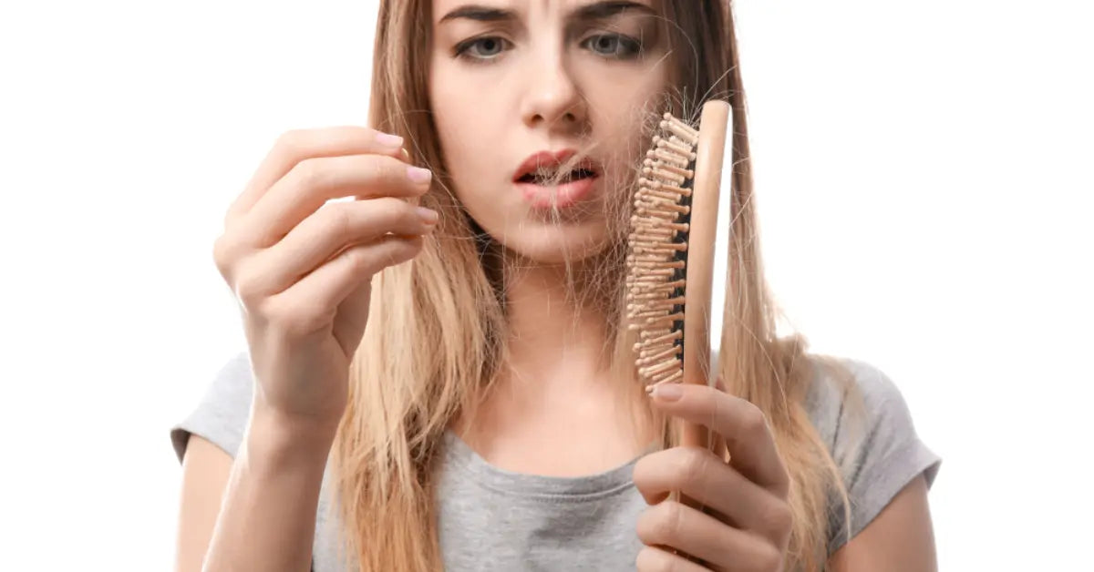 Woman looking at a hairbrush showing the need for a Hair loss treatment