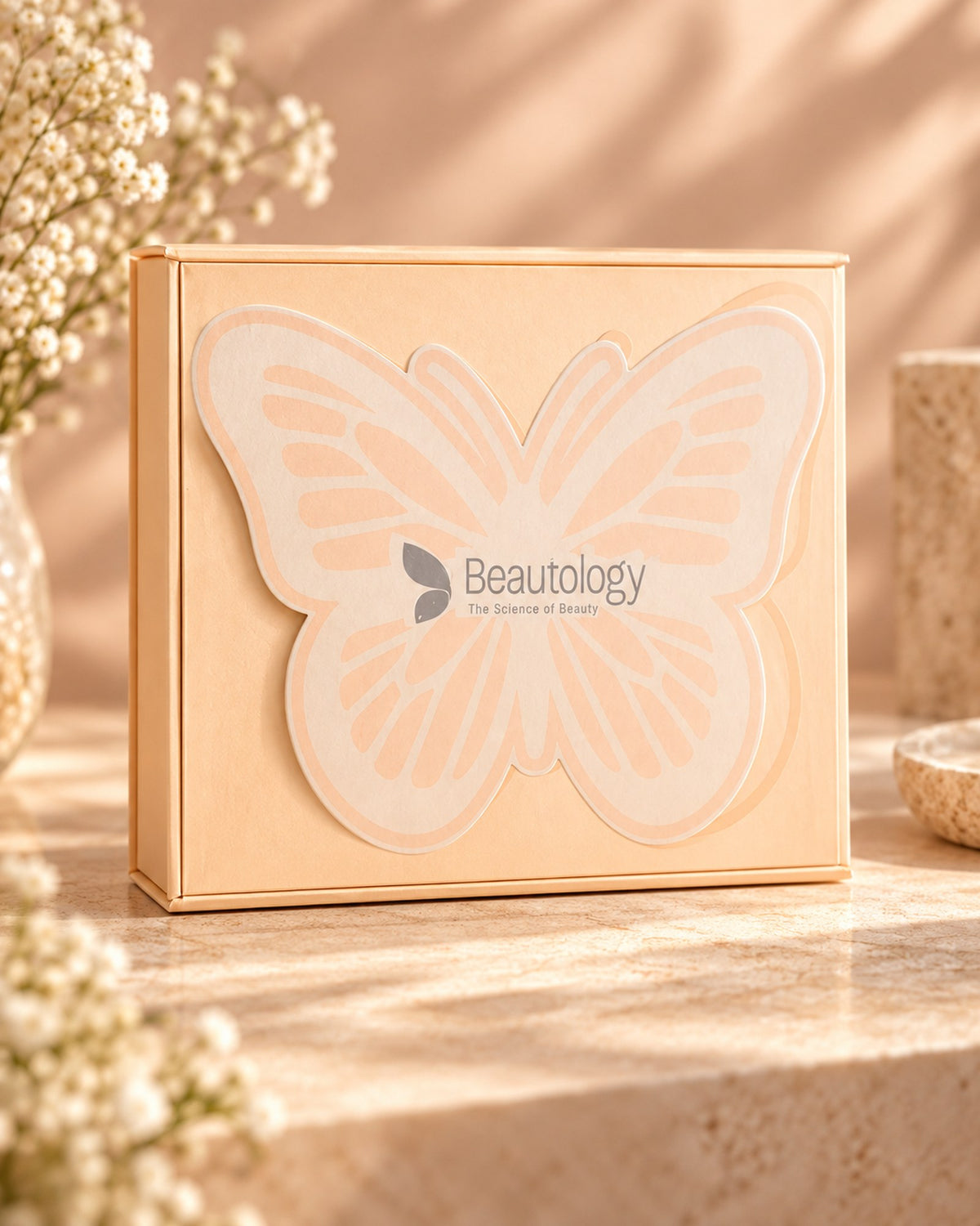 The Beautology Butterfly Box: a peach gift box with a butterfly-shaped lid in warm sunlight